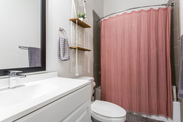 A bathroom with a white sink, a toilet, and a pink shower curtain.