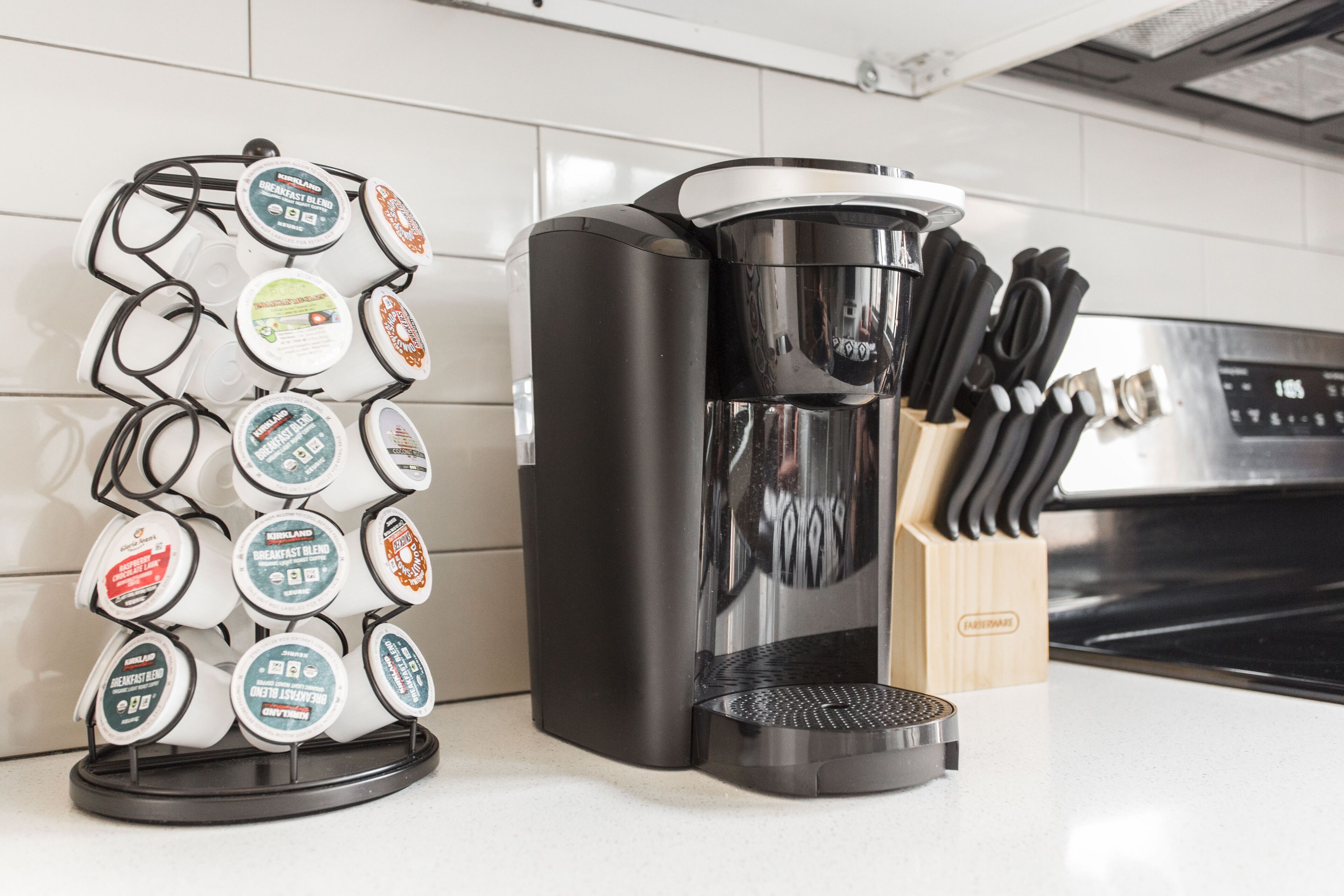 Een koffiezetapparaat en een houder voor koffiekapsules op een aanrecht.