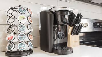 Een koffiezetapparaat en een houder voor koffiekapsules op een aanrecht.