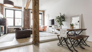 Ein großzügiger Wohnbereich mit großem Fenster, einer Couch, einem Couchtisch und einem Esstisch mit Stühlen.