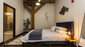 A bedroom with a bed, a bedside table, a wall-mounted lamp, and a mirror. - Loft in the Rivermarket District! Rooftop access and DT KC views. Walk to City Market, local coffee shops, restaurants, shops or hop on the free streetcar just steps away. Minutes from  P&L, T-Mobile, Crossroads, Plaza. 10 min drive to stadiums. (Kansas City)