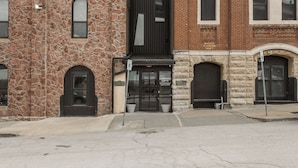 A building with a stone facade, a black entrance, and a brick section. - Exposed brick, wood beams, & chic touches give this loft serious style. Enjoy skyline views from the rooftop, a full kitchen with coffee bar, king bed, on-site gym, & quick access to the free KC streetcar. Walk to shops/dining, and the City Market! (Kansas City)