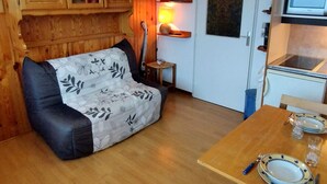 Une pièce chaleureuse avec un canapé en bois, une table à manger avec des assiettes et des verres, une lampe et un four à micro-ondes.