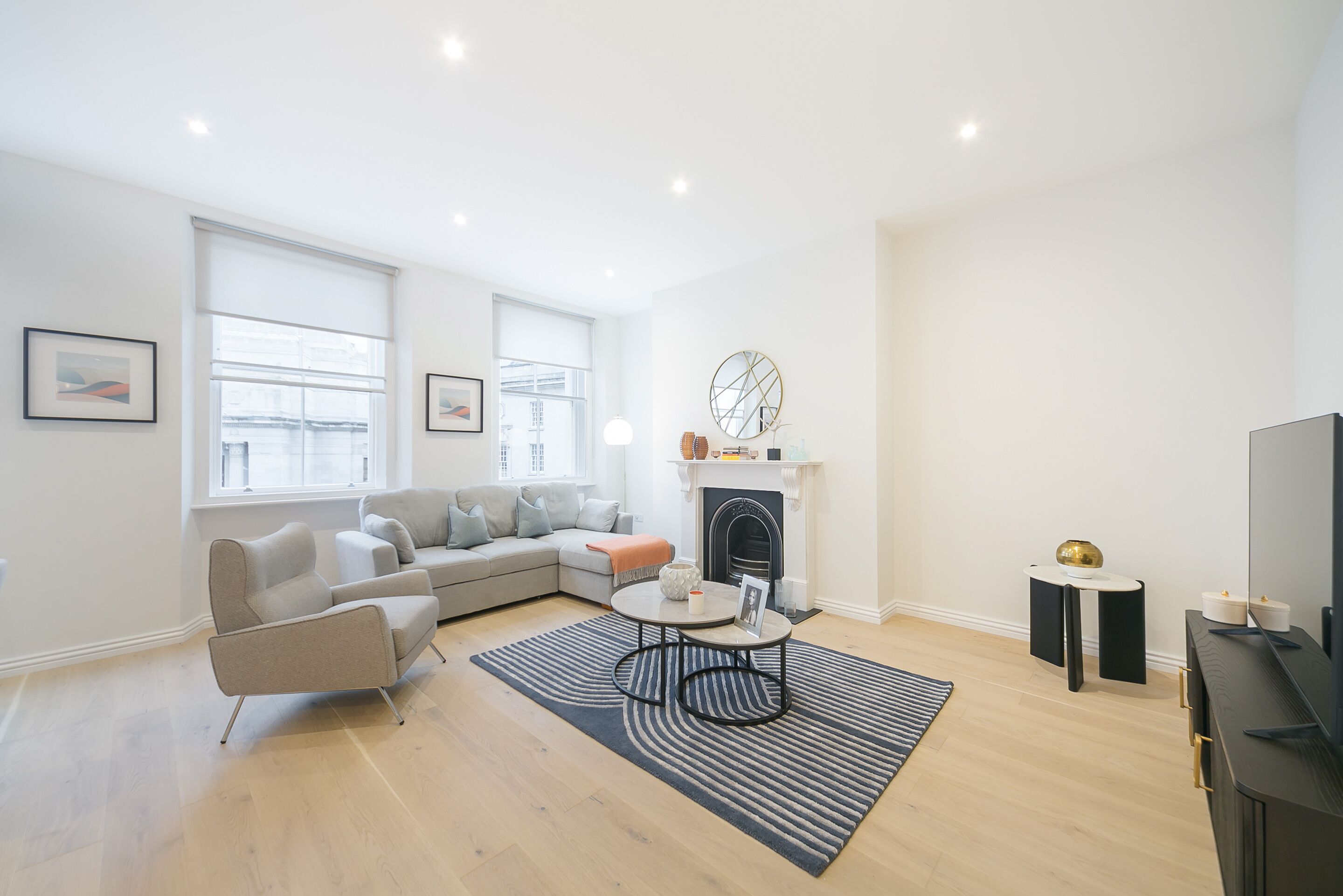 A modern living room with a sofa, armchair, coffee table, fireplace, and a TV.