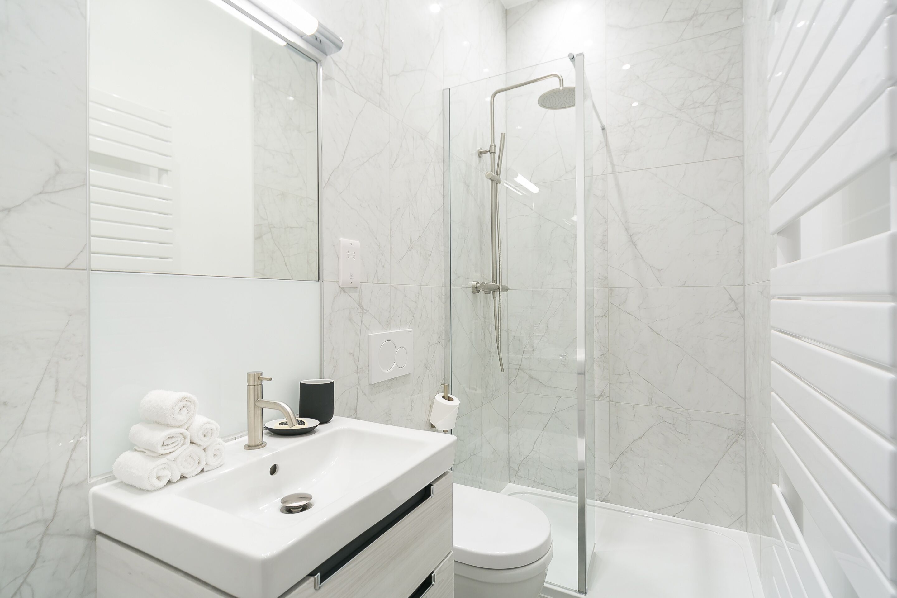 A modern bathroom with a glass-enclosed shower, a white sink, and a toilet.
