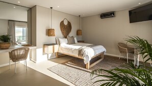 Ein modernes Schlafzimmer mit Bett, Nachttischen, einem Fernseher und einem Essbereich.
