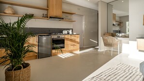 Eine moderne Küche mit Holzschränken, einem eingebauten Ofen und einem Kühlschrank. Auf der Arbeitsfläche steht ein Blumentopf und ein gewebter Korb.