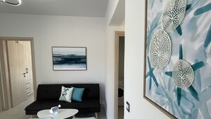 A modern room with a sofa, a dining table, and a wall-mounted artwork.