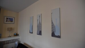 A living room with a fireplace, a lamp, and three abstract paintings on the wall.