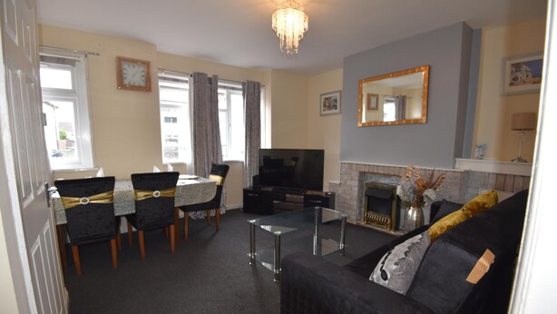 A living room with a sofa, TV, fireplace, dining table, and chairs.