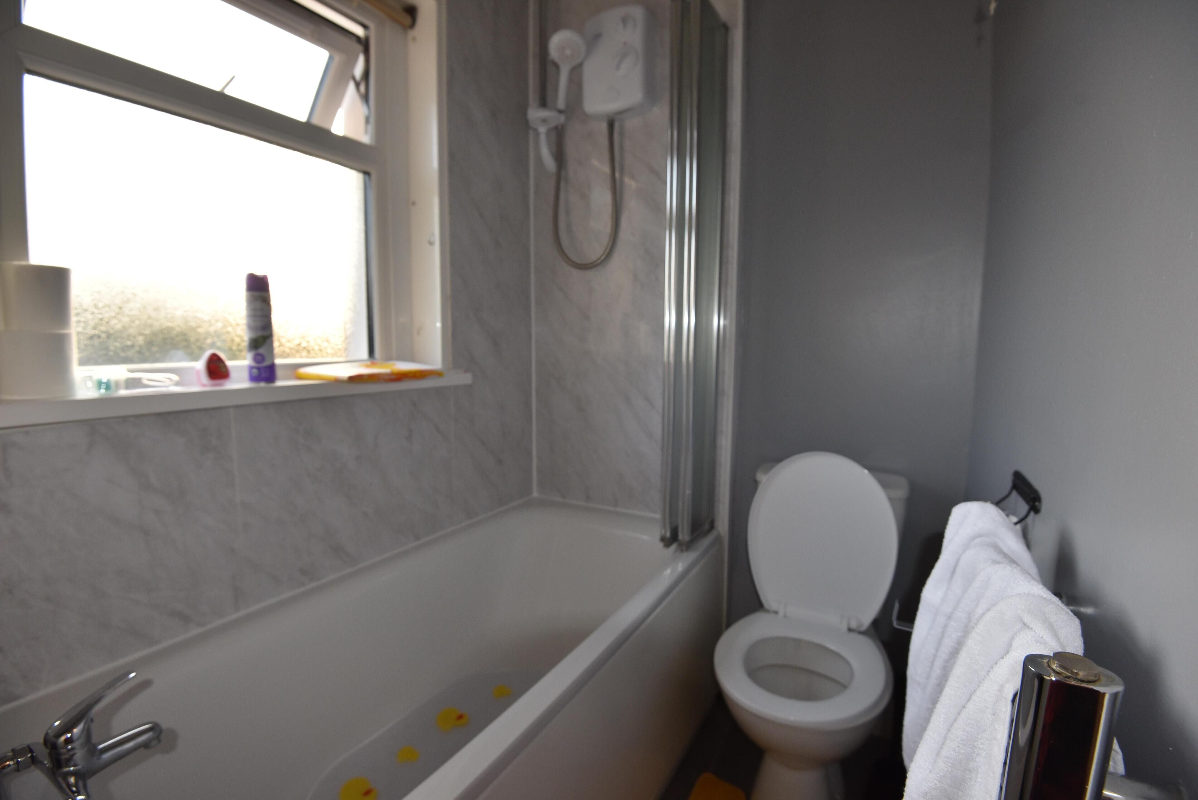 A bathroom with a bathtub, toilet, and a window.