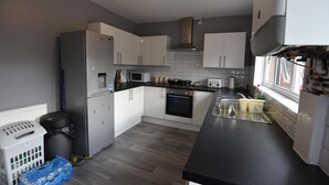 A kitchen with white cabinets, a microwave, an oven, and a sink.