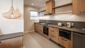A modern kitchen with wooden cabinets, a built-in oven, microwave, and dishwasher.