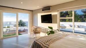 A modern bedroom with a large bed, a TV mounted on the wall, and a balcony with a pool. - View 16 | Boho Bliss (Cape Town)