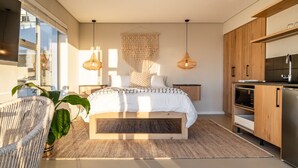 A modern bedroom with a large bed, bedside tables, a hanging light fixture, and a view of the city through a large window. - View 16 | Boho Bliss (Cape Town)