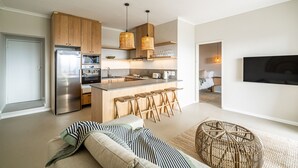 Una cocina moderna con gabinetes de madera, un refrigerador de acero inoxidable y una barra con taburetes.