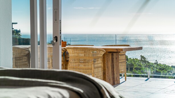 Ein Balkon mit Korbmöbeln und Meerblick.