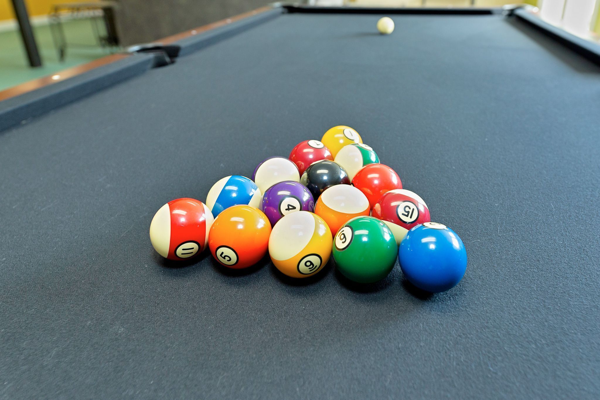 A pool table with a triangular arrangement of billiard balls.