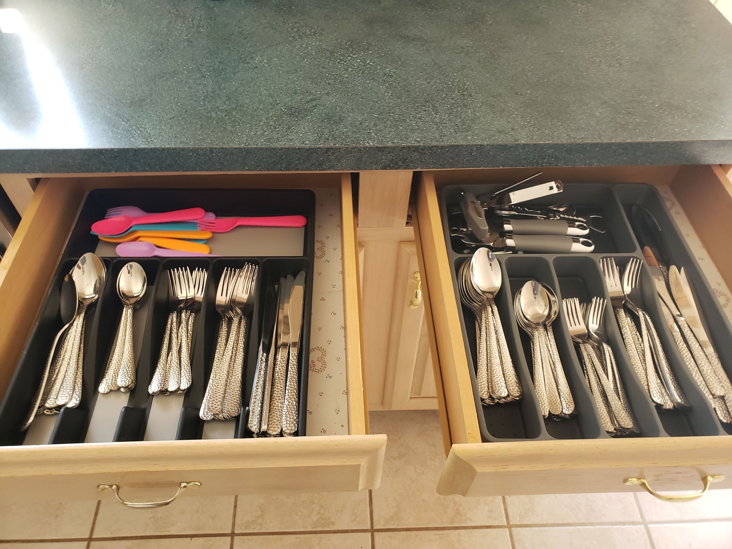 Two drawers with utensils, including spoons, forks, and knives, organized in compartments.