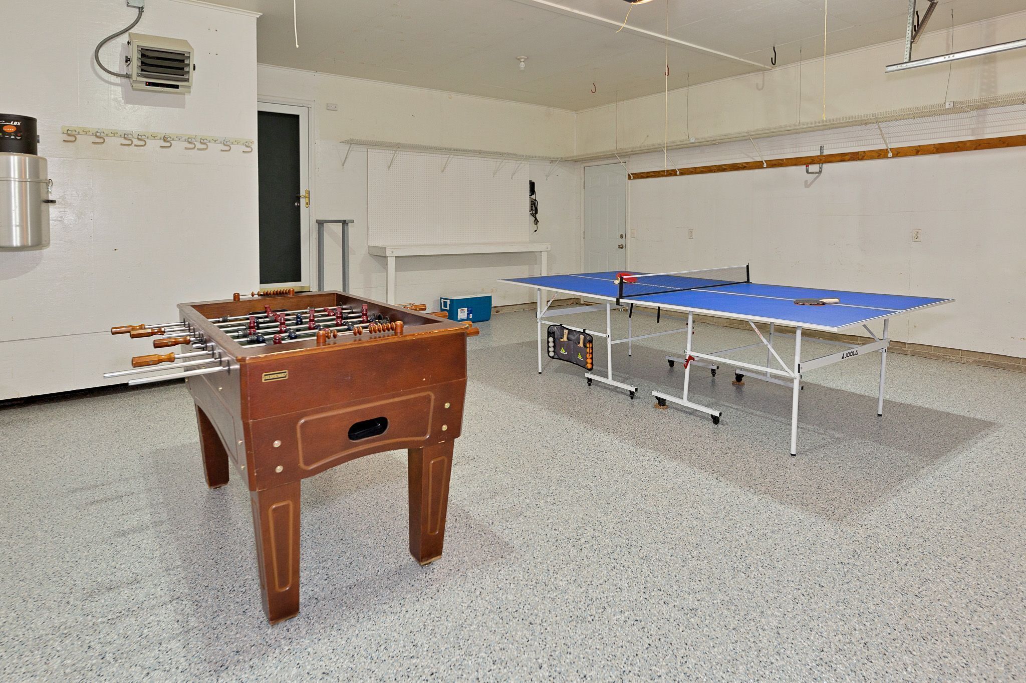 Een kamer met een tafelvoetbaltafel, een pingpongtafel en een blauwe opbergunit.