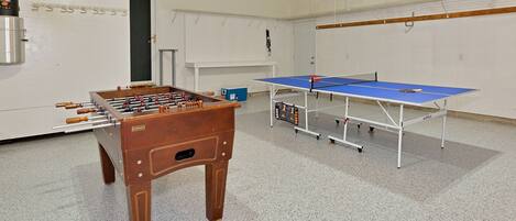 Een kamer met een tafelvoetbaltafel, een pingpongtafel en een blauwe opbergunit.