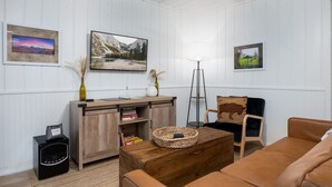 A living room with a wooden cabinet, a sofa, a coffee table, and a lamp. There are framed pictures on the wall. - Aspen Ridge Retreat (Greer)