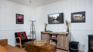 A cozy living room with a wooden cabinet, a television, and a fireplace. - Aspen Ridge Retreat (Greer)