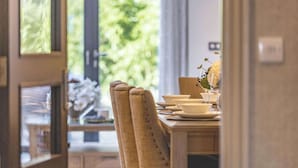 Comedor con mesa de madera dispuesta para cuatro personas, sillas y un florero con flores.