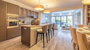 Una cocina moderna con una isla central, taburetes de bar e iluminación colgante.