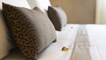 Una cama bien hecha con almohadones estampados y un adorno dorado sobre el edredón.