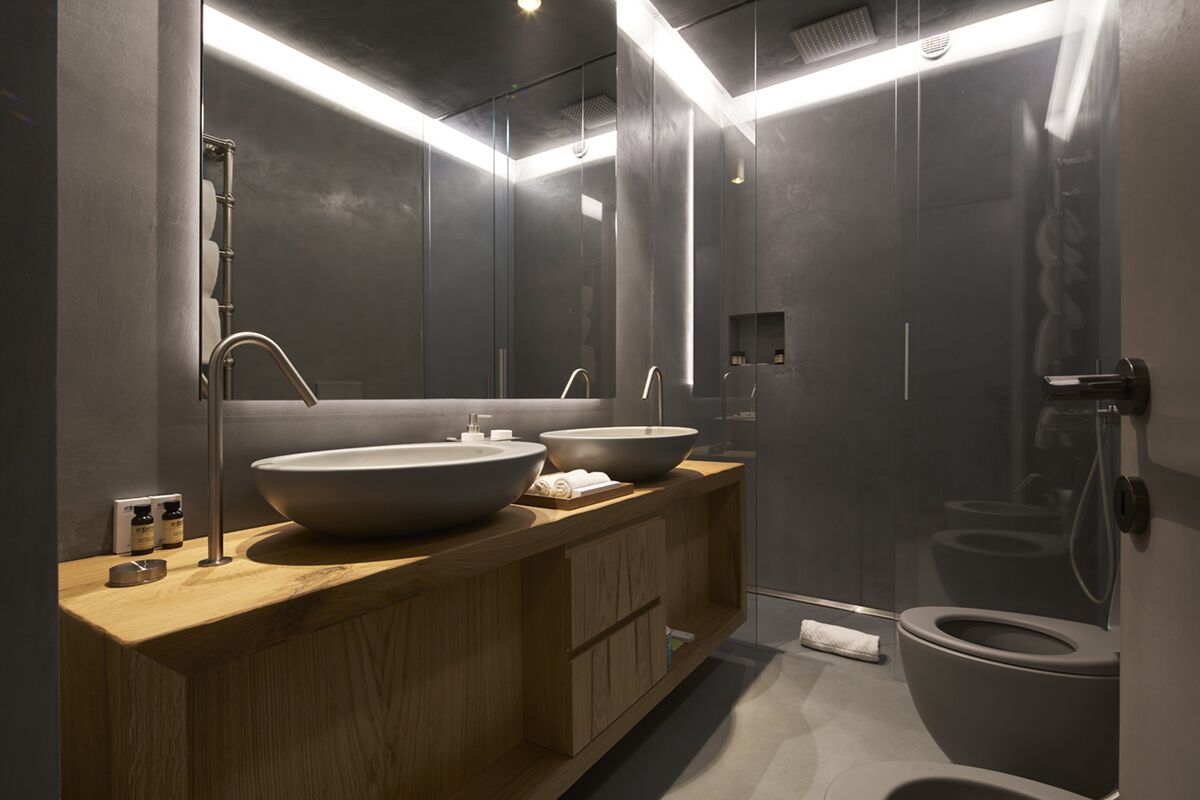 A modern bathroom with two large sinks, a shower, and a toilet.