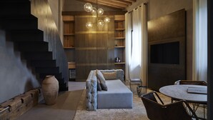 A modern living room with a sofa, a dining table, and a staircase. - Fornace Suite (Florence)