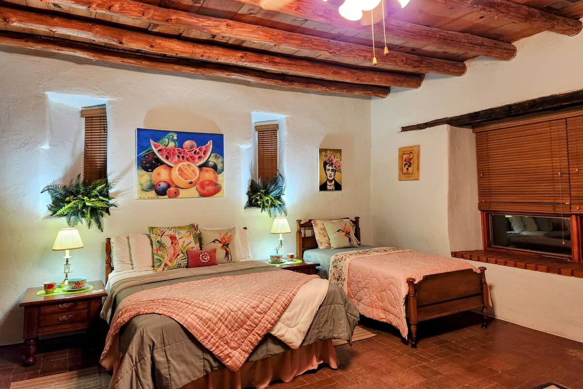 Una habitación acogedora con dos camas, vigas de madera en el techo y un ventilador.