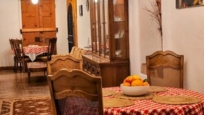 Zona pranzo con tavolo in legno, sedie, un mobile e un lampadario.