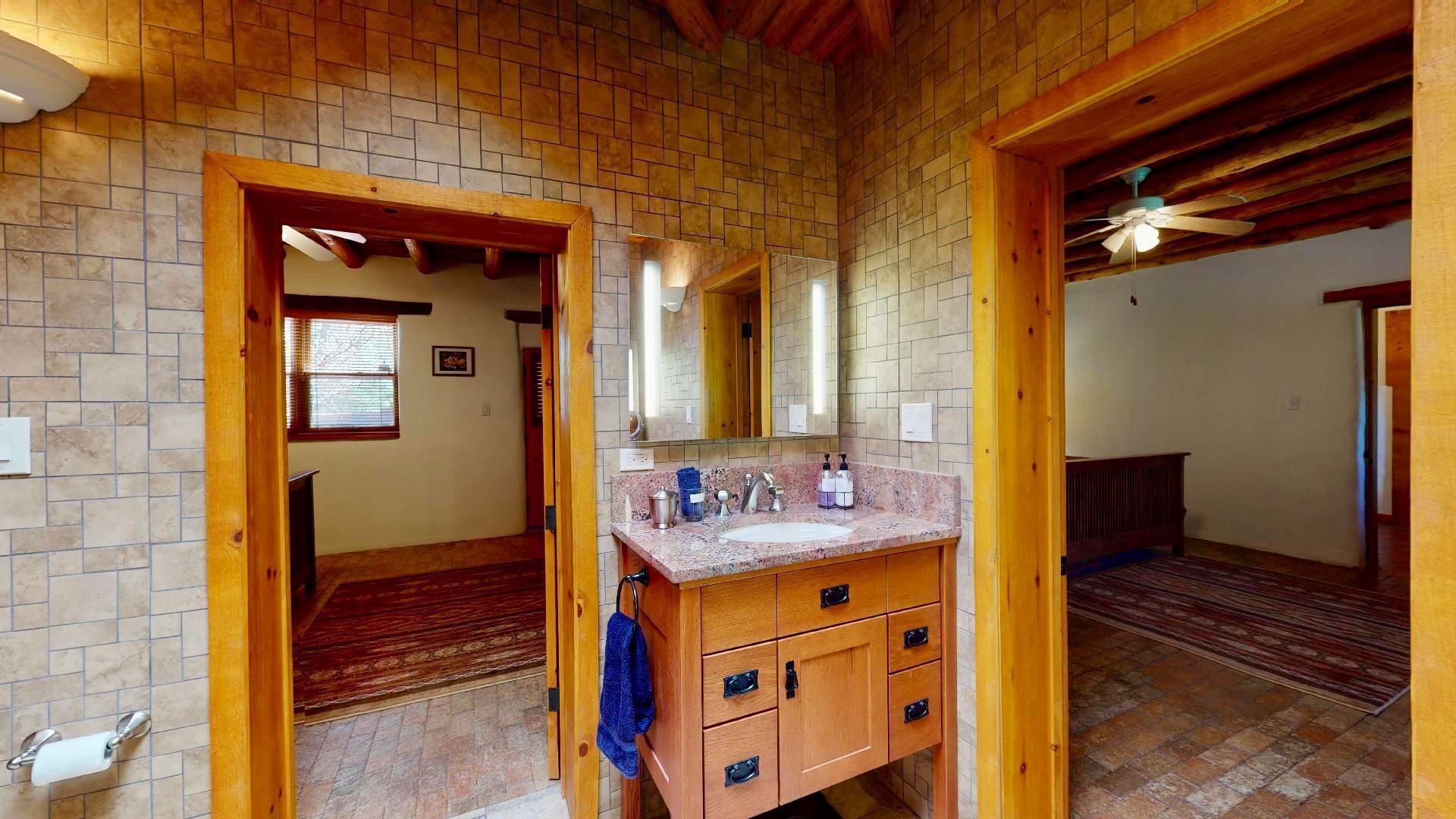 A bathroom with a wooden vanity, a large mirror, and a tiled floor.