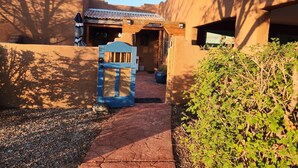 Un sentiero conduce a un edificio con un cancello blu, circondato da mura e vegetazione.