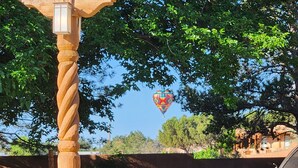 Una mongolfiera nel cielo, un palo di legno contorto e un edificio con tetto spiovente.