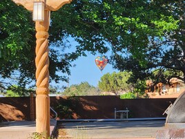 Um balão de ar quente no céu, um poste de madeira retorcido e um edifício com telhado inclinado.