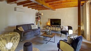 Una sala de estar con sofá, sillón, mesa de centro y televisor.