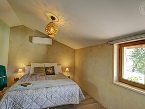 A bedroom with a bed, two bedside lamps, a window, and a ceiling light fixture.