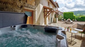 Un jacuzzi con una terraza de madera y vistas a un paisaje campestre.