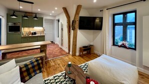 Une cuisine moderne avec des meubles de couleur verte, une table à manger en bois et un téléviseur fixé au mur.