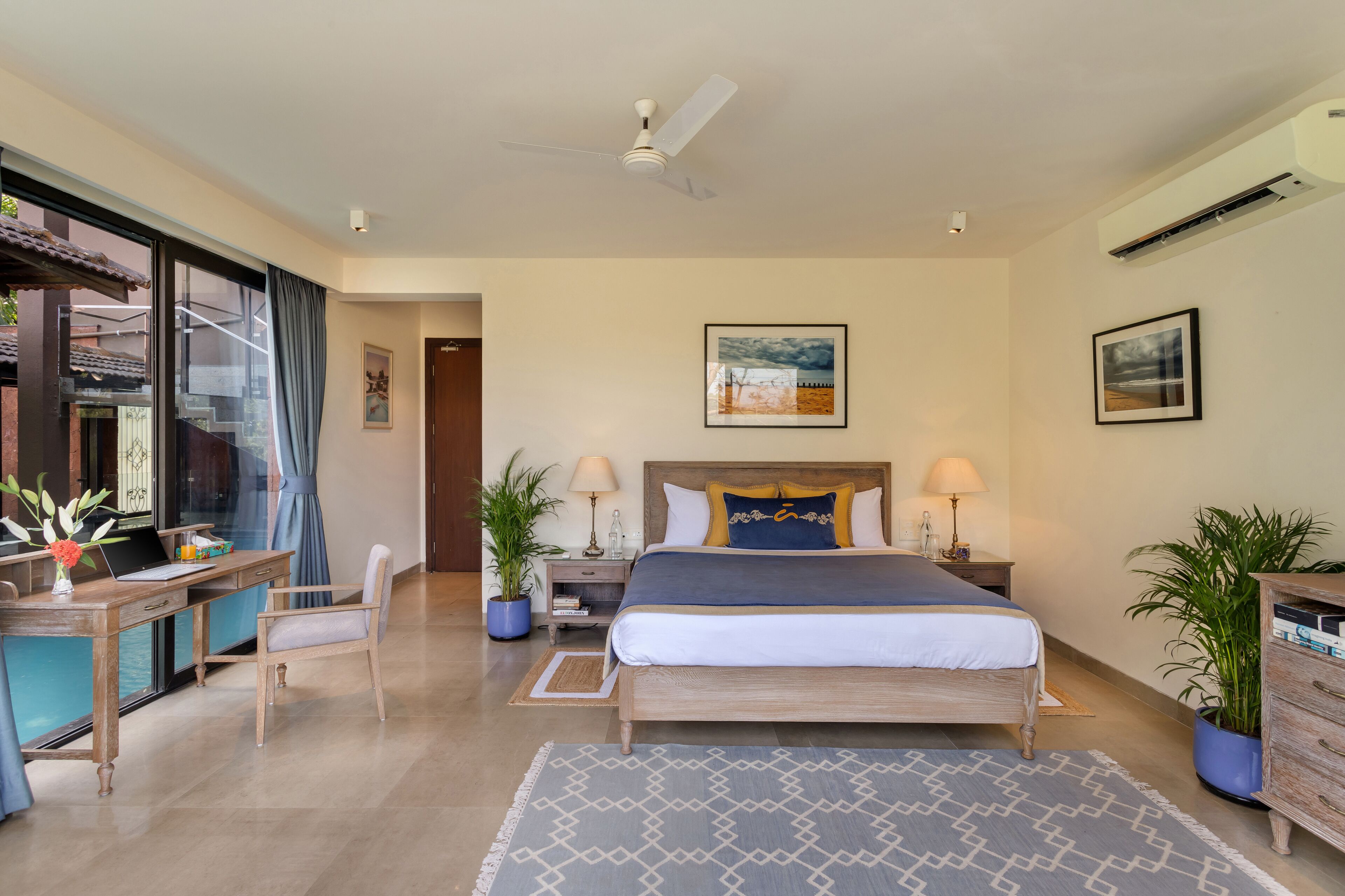 Un dormitorio con cama, escritorio, silla y plantas en macetas.