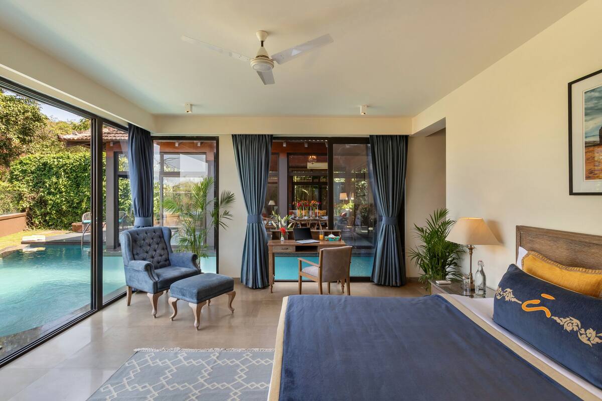 A bedroom with a large bed, a desk, and a view of a swimming pool.