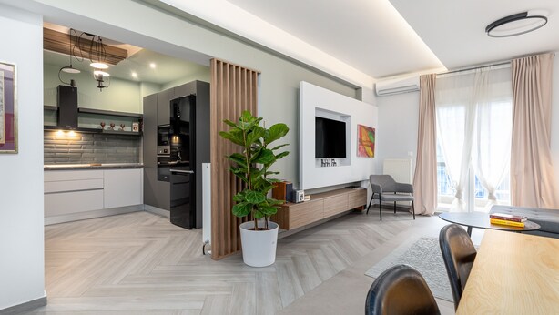 A modern living space with a kitchen, dining area, and a TV mounted on the wall. - Amazonia Apt by halu! (Thessaloniki)