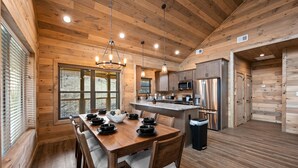 A wooden cabin-style kitchen with a dining table, chairs, and a central island.