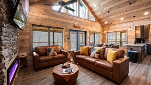 A spacious living area with leather sofas, a coffee table, and a stone fireplace.