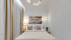 Un dormitorio ordenado con una cama grande, una mesita de noche con lámpara y un aplique de pared.