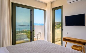 A hotel room with a bed, a TV, a wooden side table, and a balcony with a chair.