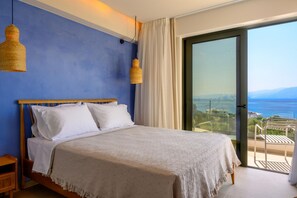 A bedroom with a bed, white pillows, a beige blanket, and two hanging lamps.